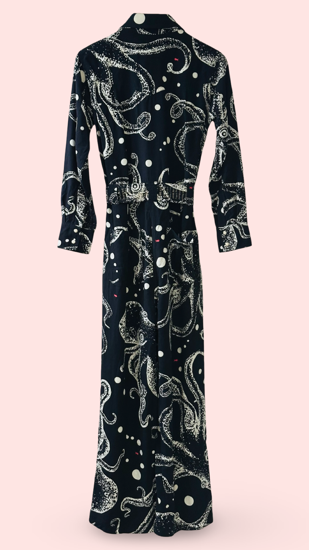The back of navy jumpsuit with white octopus pattern and small red fishes on a pink background