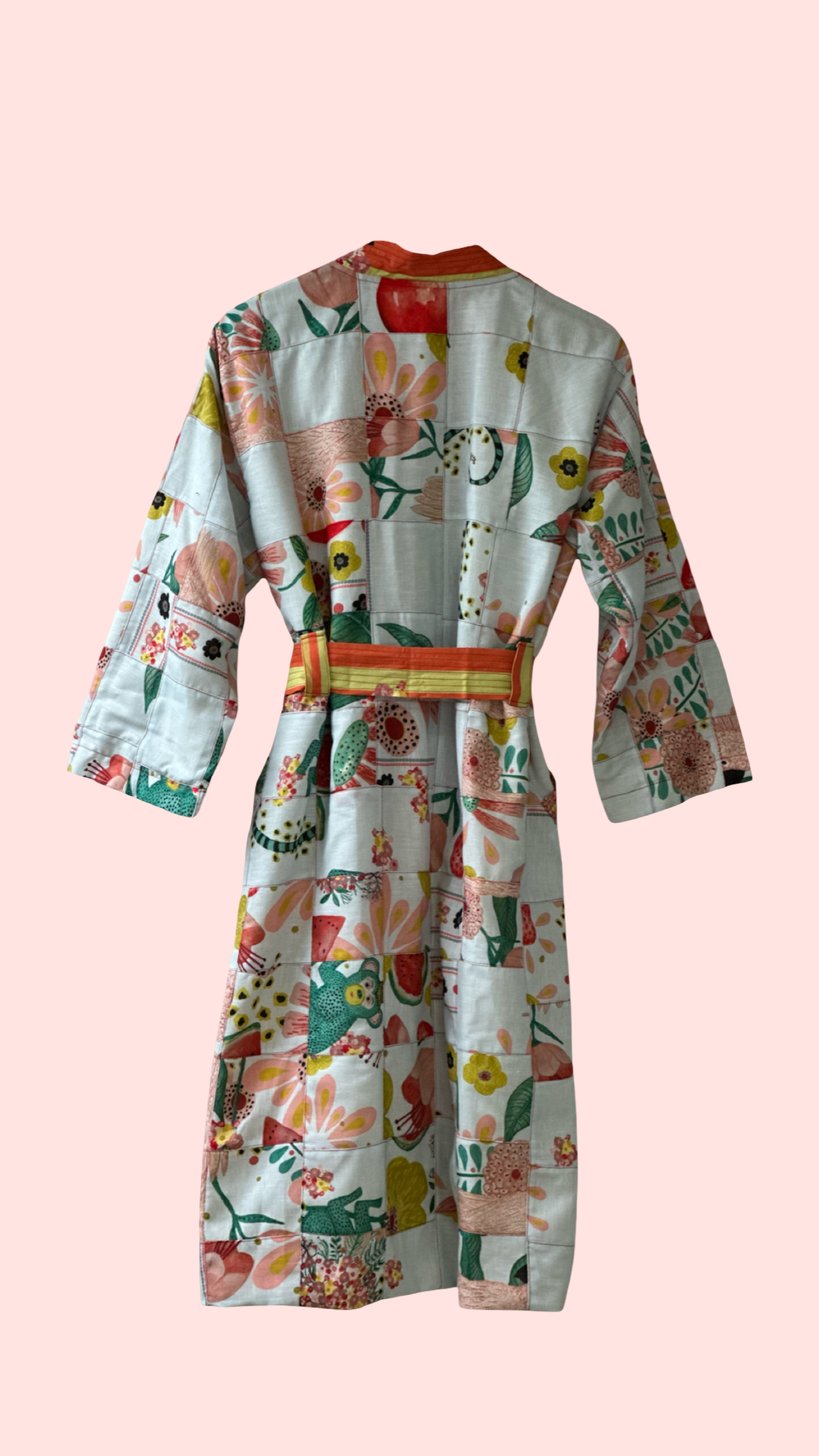 Back view of hand-illustrated coat featuring patchwork-style artwork tied at the waist