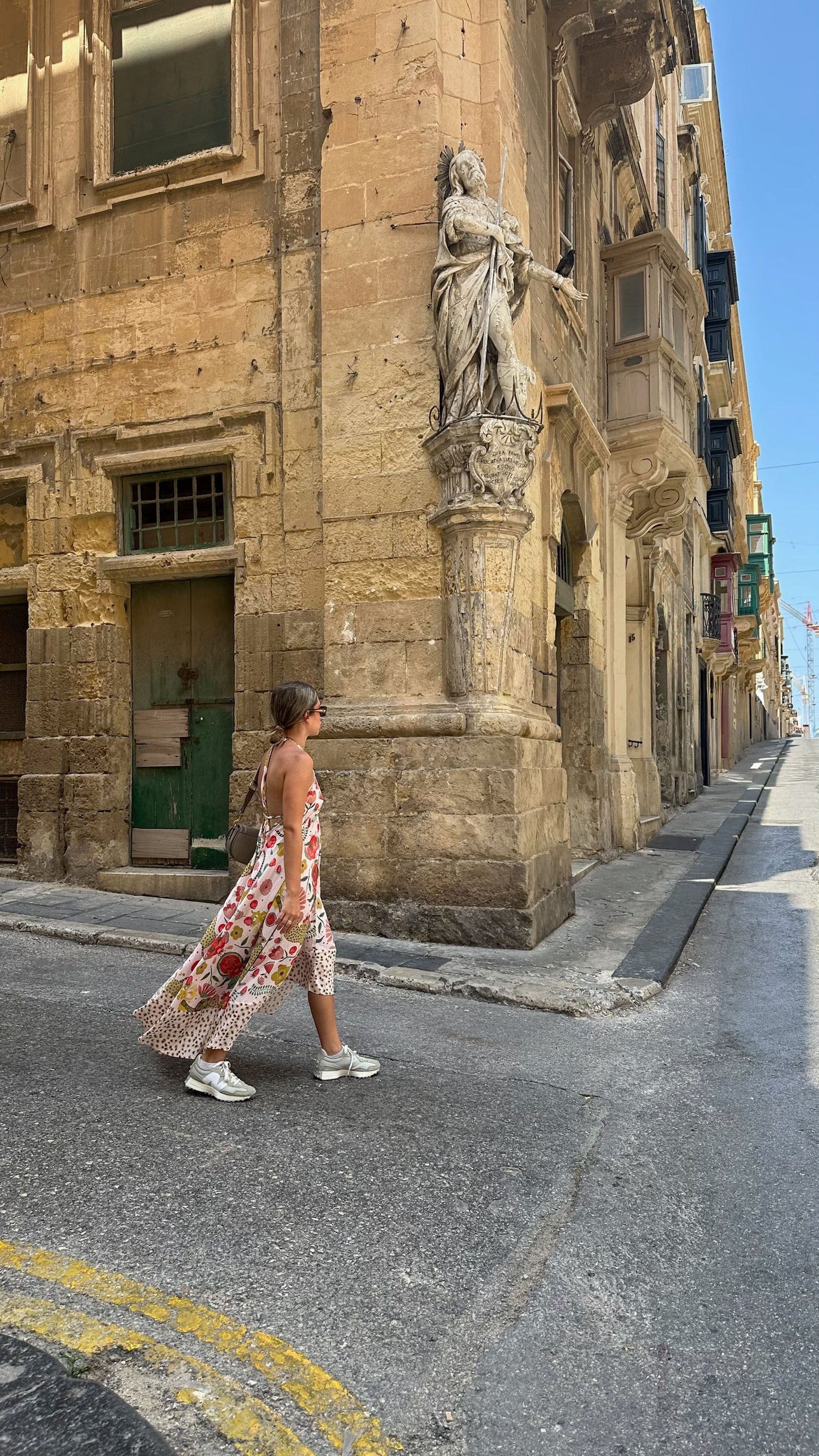 Woman walking on a street with a statue in front of an old building